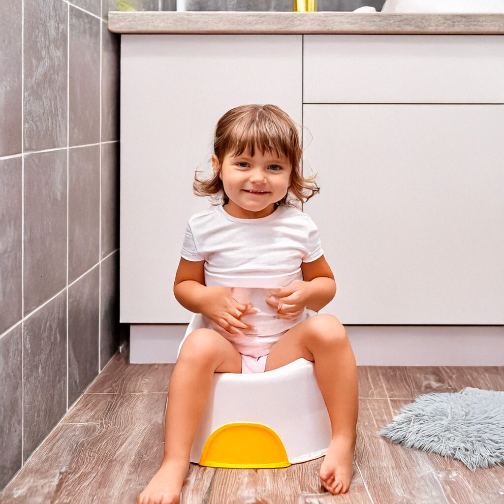 Una bambina sorridente è seduta sopra al vasino